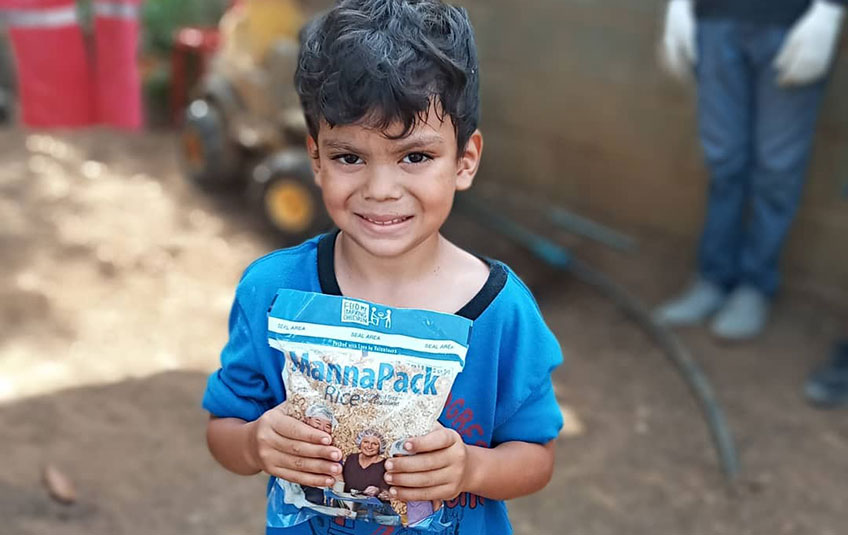 A boy holds a bag of MannaPack Rice