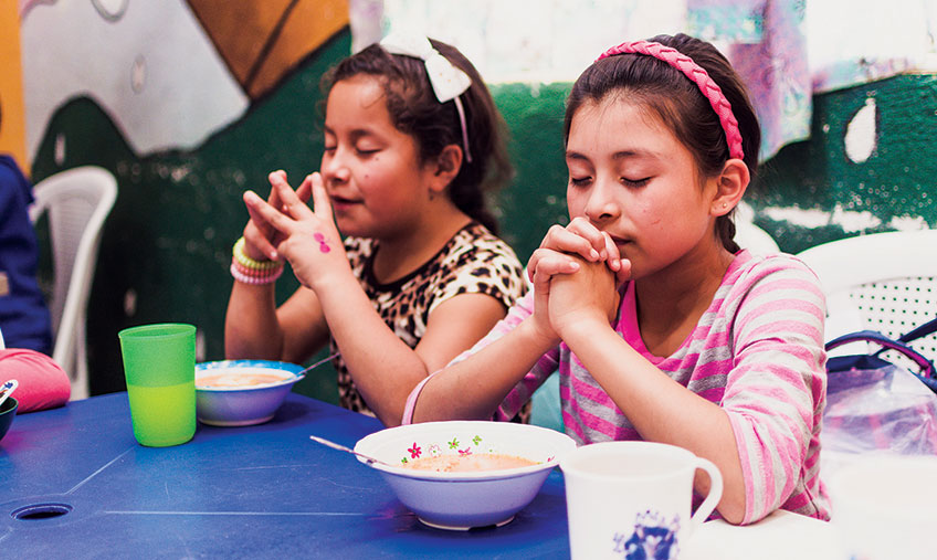 girls praying before eating FMSC food