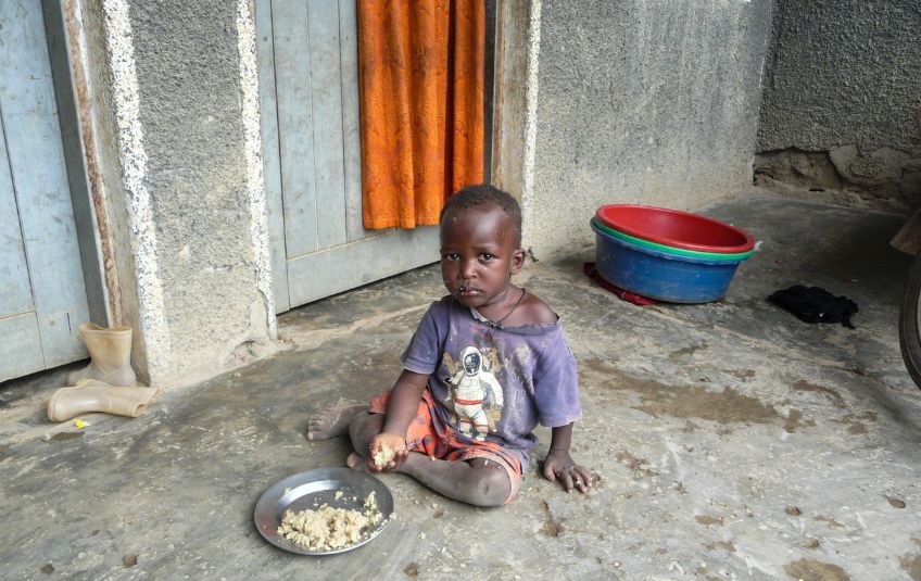 child on ground with plate of rice