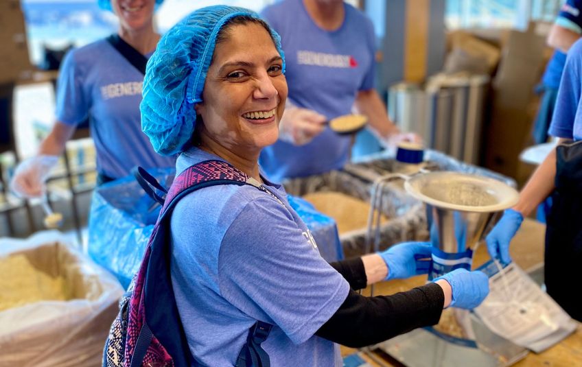 Woman filling bag of MannaPack at Target Field for Pack at the Park MobilePack. 