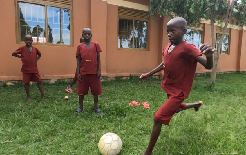 Ugandan teens playing soccer in red uniforms
