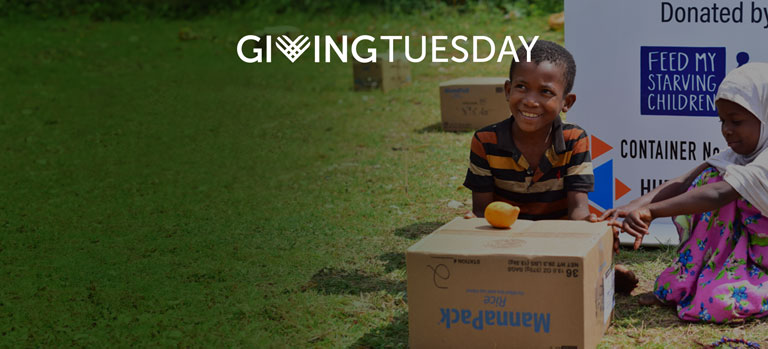 A boy and girl in sitting behind an FMSC food box. The Giving Tuesday logo is at the top.